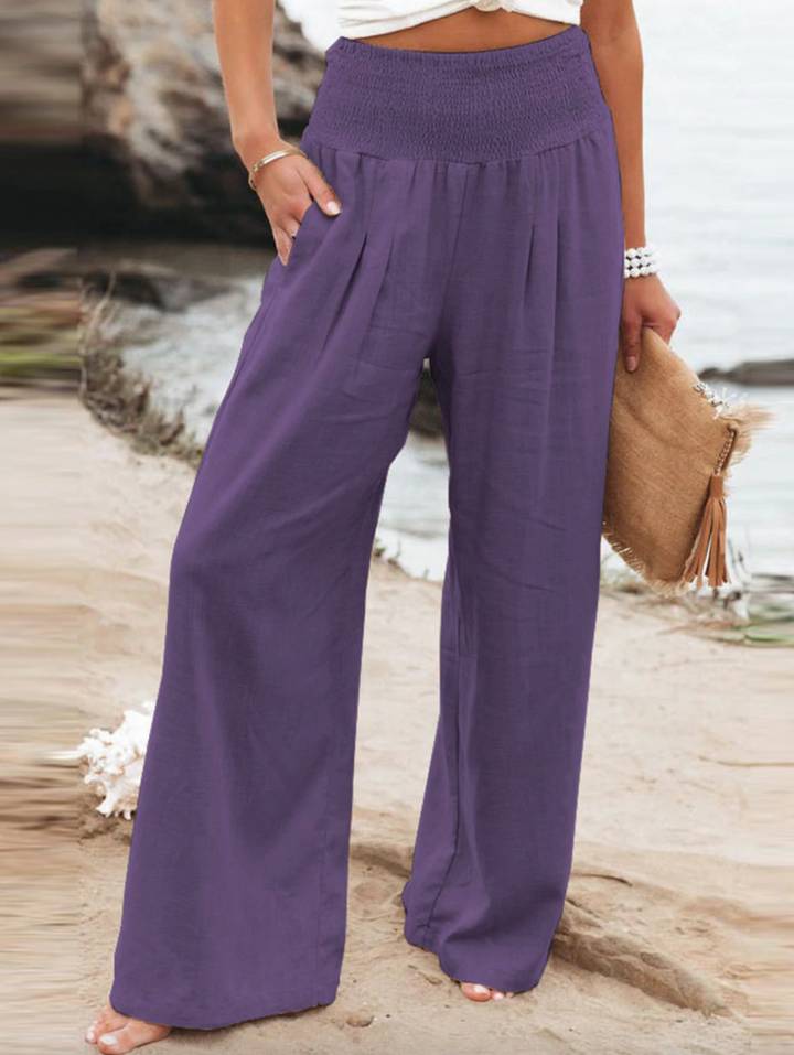 Frau in lila Leinenhose am Strand, Sommermode, lässig, bequem, Damenbekleidung.