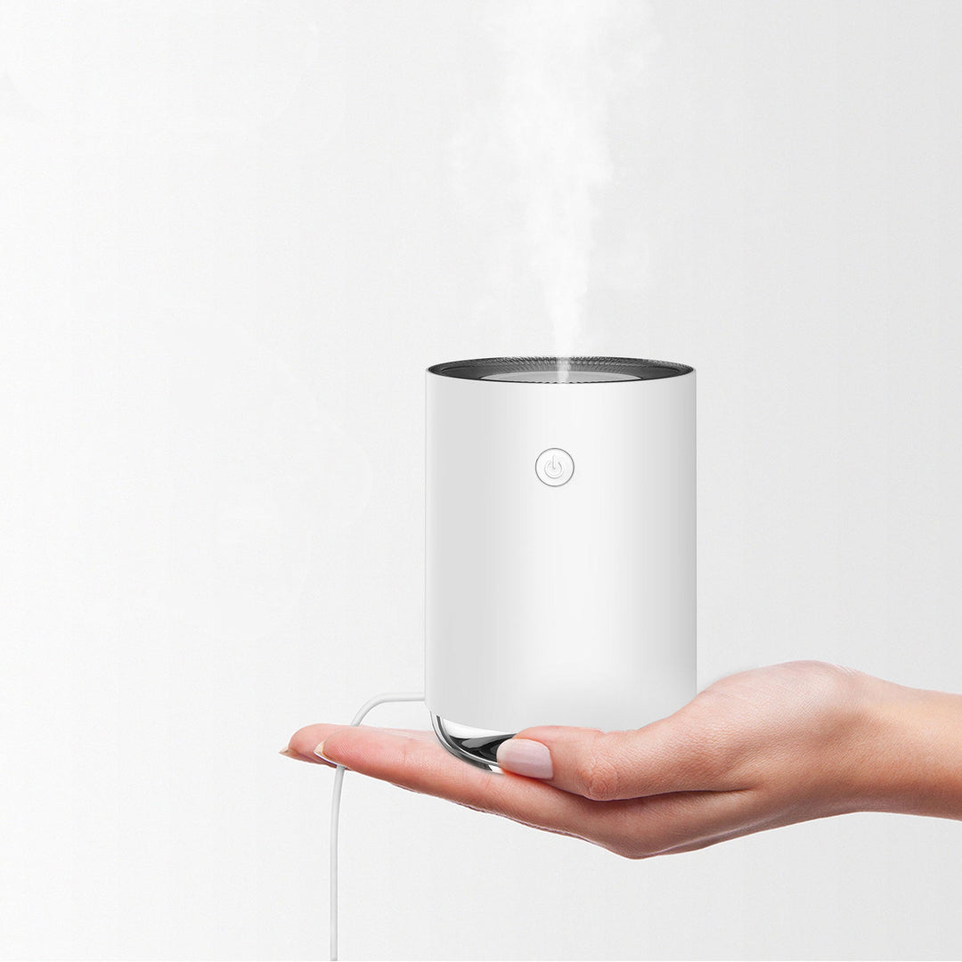 Weißer Luftbefeuchter auf Hand, kompakt, modern, USB-betrieben, für Raumklima, minimalistisch.