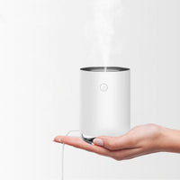 Weißer Luftbefeuchter auf Hand, kompakt, modern, USB-betrieben, für Raumklima, minimalistisch.