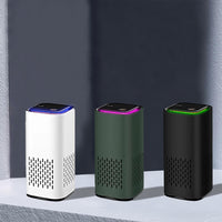 Drei tragbare Luftreiniger in Weiß, Grün und Schwarz auf grauem Hintergrund.