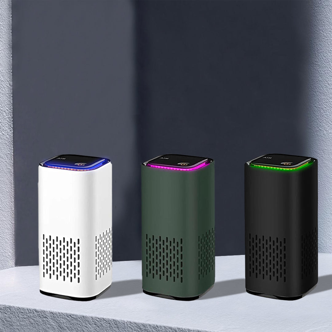 Drei tragbare Luftreiniger in Weiß, Grün und Schwarz auf grauem Hintergrund.