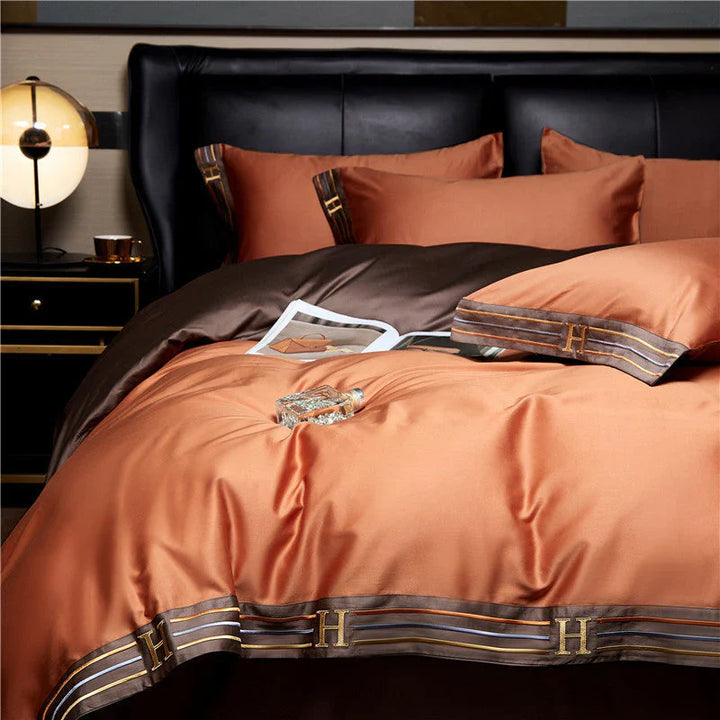 Luxuriöse orange-braune Bettwäsche-Set aus Satin mit H-Monogramm, elegant und stilvoll.