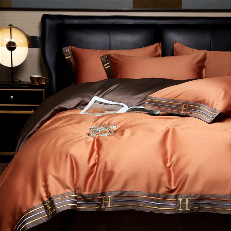 Luxuriöse orange-braune Bettwäsche-Set aus Satin mit H-Monogramm, elegant und stilvoll.
