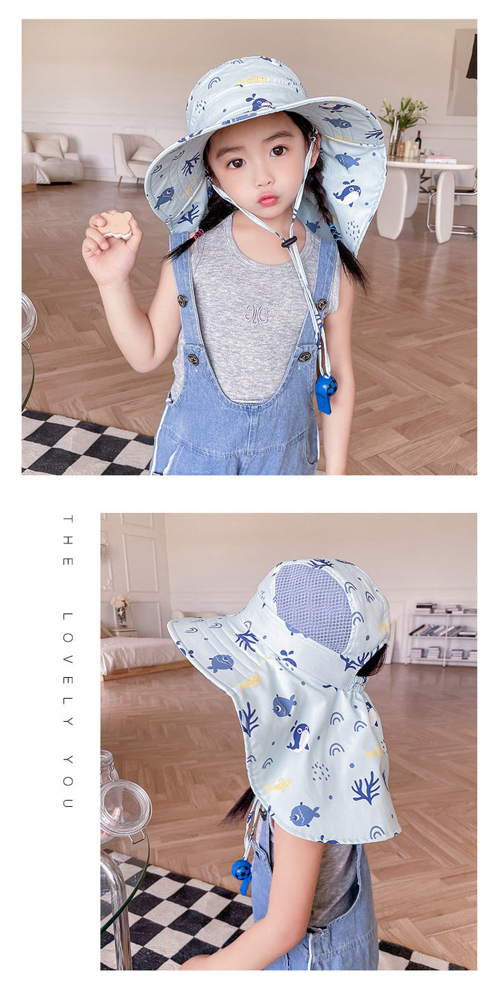 Mädchen mit blauem Sonnenhut, grauem Shirt und Latzhose in modernem Wohnzimmer.