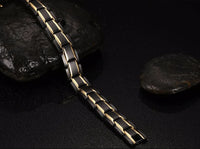 Schwarzes magnetisches Armband aus Edelstahl mit goldenen Akzenten auf schwarzem Hintergrund.