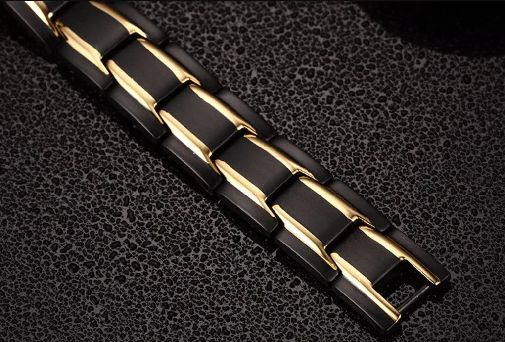 Schwarzes und goldenes magnetisches Armband aus Edelstahl auf strukturiertem Hintergrund.