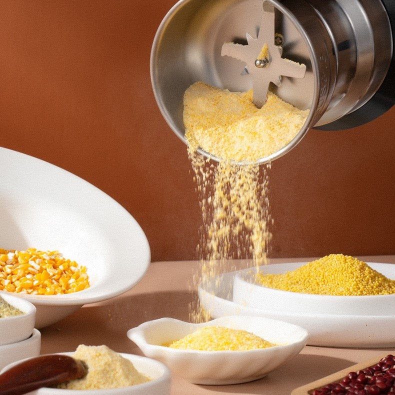 Metallische Getreidemühle mahlt gelben Mais zu feinem Mehl, umgeben von Schalen mit Körnern.