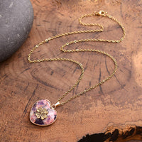 Goldene Herzanhänger-Halskette mit Blumenmotiv auf Holz, Damen-Schmuck, elegantes Design.