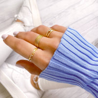 Goldener "Mama"-Ring an Hand, blaues Strickpullover, modischer Schmuck, Damenaccessoire.
