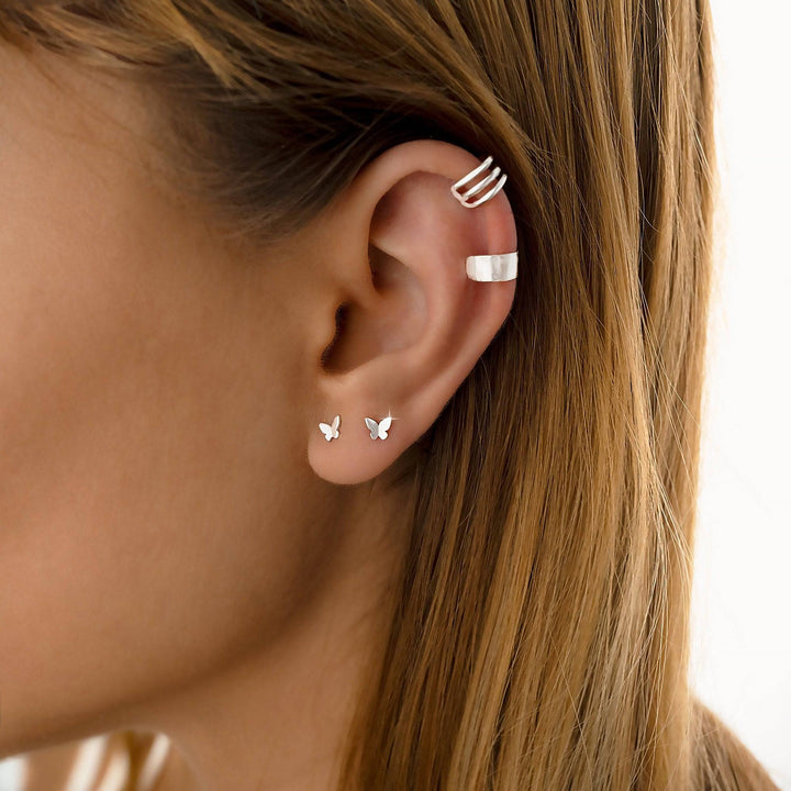 Frau mit silbernen Schmetterling-Ohrringen, minimalistischer Schmuck, Nahaufnahme.