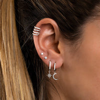 Frau mit silbernen Mini-Sterne-Ohrringen und Mondanhänger, modischer Schmuck, Nahaufnahme.