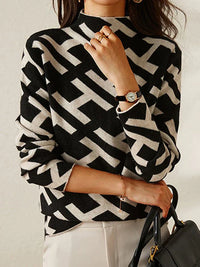 Frau in schwarz-weißem geometrischem Pullover, Armbanduhr, schwarze Handtasche.