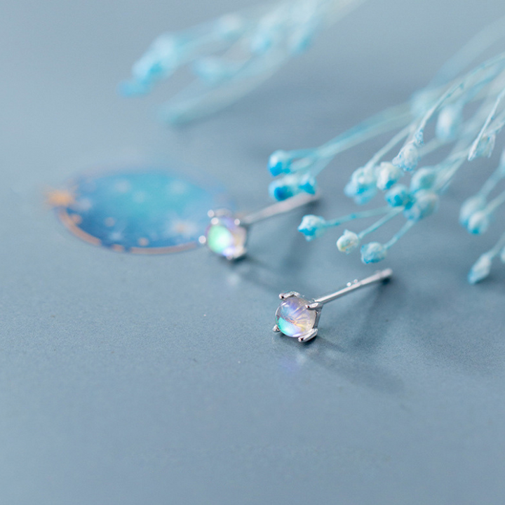 Silberne Ohrringe mit Opalsteinen, elegantes Design, auf blauem Hintergrund.