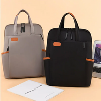 Zwei moderne Laptop-Rucksäcke, schwarz und grau, mit Lederdetails, auf beigem Hintergrund.