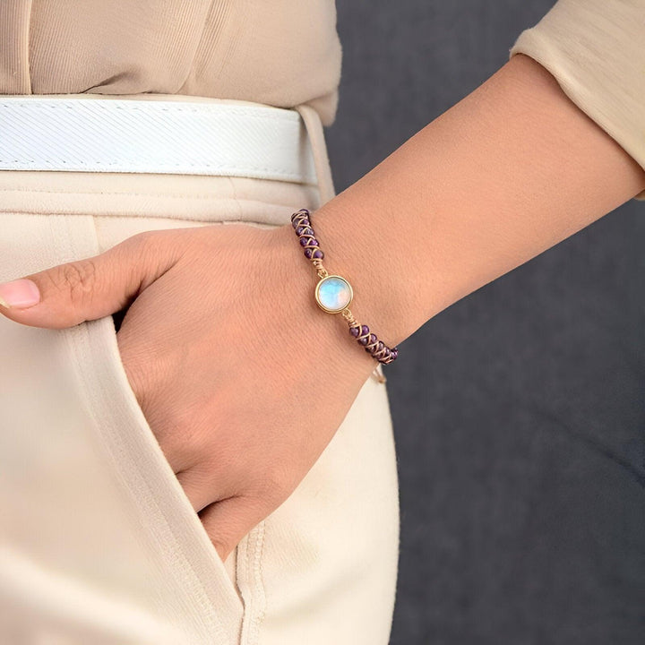 Frau mit lila Armband aus Leder und Mondstein, elegantes Schmuckdesign, Nahaufnahme.