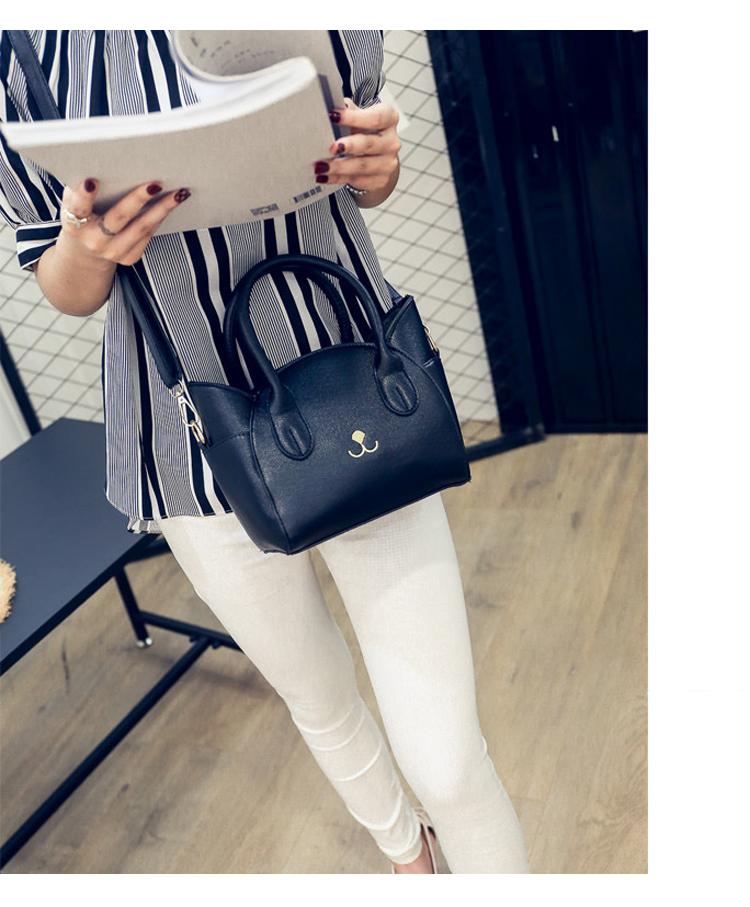 Frau mit schwarzer Lederhandtasche, Katzenmotiv, gestreiftes Hemd, weiße Hose, modern.