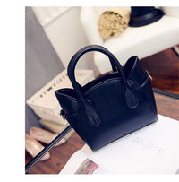 Schwarze Lederhandtasche auf Glastisch, elegantes Design, Damenmode-Accessoire.