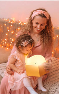 Frau und Kind mit leuchtender Wal-Lampe, rosa Kleidung, gemütliche Atmosphäre, Lichterkette.