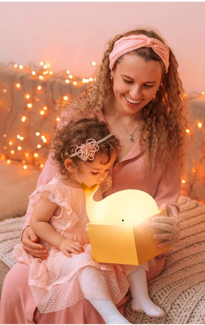 Frau und Kind mit leuchtender Wal-Lampe, rosa Kleidung, gemütliche Atmosphäre, Lichterkette.