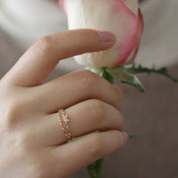 Hand mit goldfarbenem Ring und Rose, Schmuck, elegantes Design, Damenmode, Accessoire.