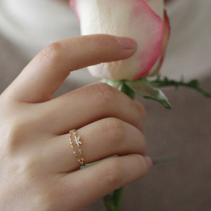 Hand mit goldfarbenem Ring und Rose, Schmuck, elegantes Design, Damenmode, Accessoire.