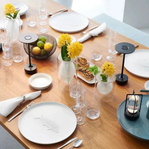 Eleganter Esstisch mit gelben Blumen, modernen Lampen und Geschirr, ideal für Restaurant-Dekor.