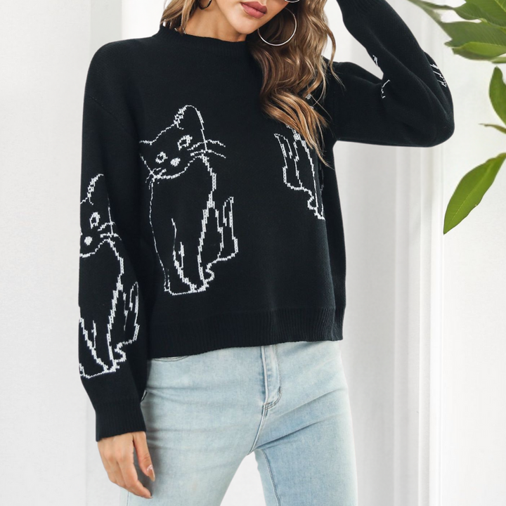 Frau trägt schwarzen Pullover mit Katzenmotiv, Damenmode, lässig, Herbst, Strick, Jeans.
