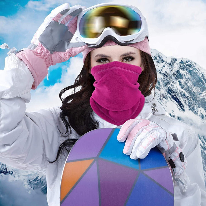 Frau mit rosa Schal und Snowboard vor verschneiten Bergen, Wintersport, Skibrille, Winterkleidung.