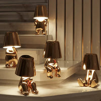 Goldene Lampen in Form von sitzenden Figuren auf Treppe, modernes Design, Innenbeleuchtung.