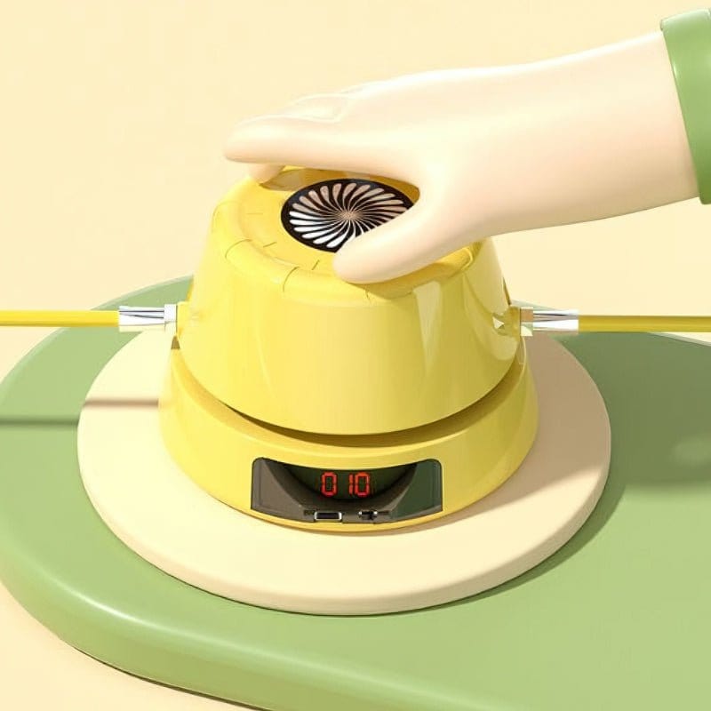 Gelbes elektronisches Spielzeug mit Hand, digitalem Display und Kabeln auf grünem Untergrund.