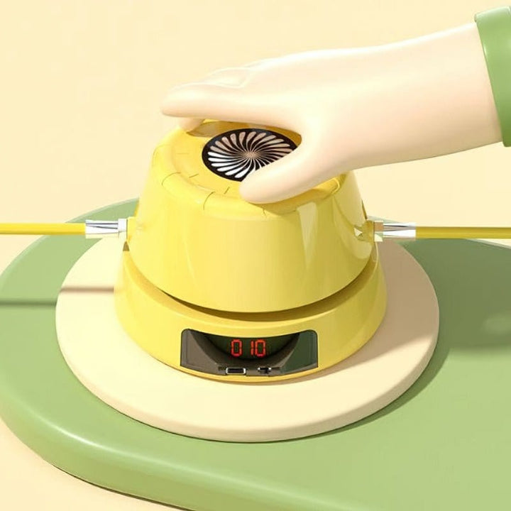 Gelbes elektronisches Spielzeug mit Hand, digitalem Display und Kabeln auf grünem Untergrund.