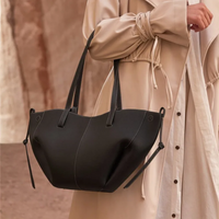 Damenhandtasche aus schwarzem Leder, elegant, modern, mit langen Henkeln, Outdoor-Hintergrund.