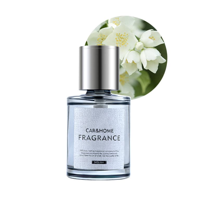 Klarer Glasflakon mit silbernem Deckel, Duft für Auto und Zuhause, weiße Blüten im Hintergrund.