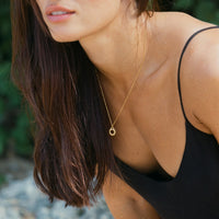 Frau mit goldener Sonnenanhänger-Halskette, Sommermode, elegantes Schmuckdesign.