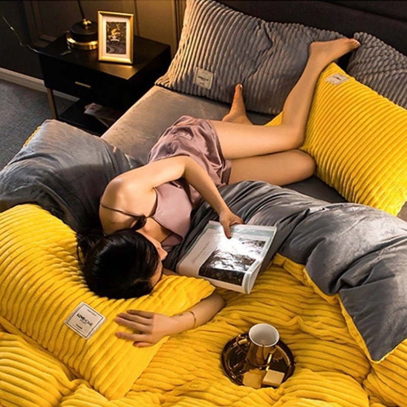 Frau entspannt auf gelbem, geripptem Winterbettdecke-Set mit Kissen, liest ein Buch.