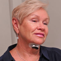 Ältere Frau mit Nackenmassagegerät, silber, tragbar, Entspannung, Schmerzlinderung, Wellness.