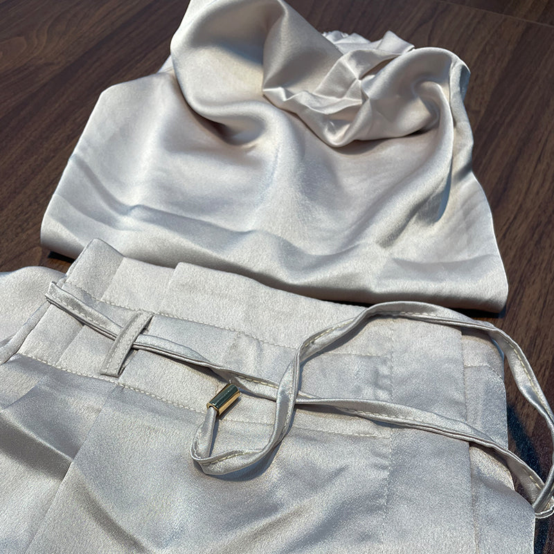 Seidenset Damen, cremefarben, bestehend aus Bluse und Hose, elegant, auf Holztisch.