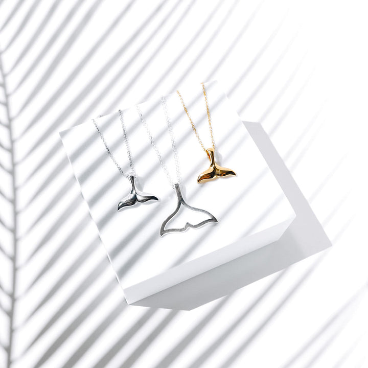 Drei Walflossen-Halsketten in Silber und Gold auf weißem Hintergrund, Schmuck, Accessoires.