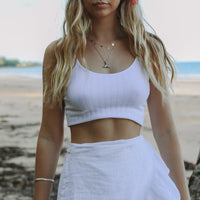 Frau am Strand mit weißem Top und Walflossen-Halskette, Sommermode, Schmuck, Strandkleidung.