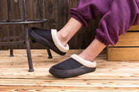 Schwarze Herren-Baumwollhausschuhe mit weißem Futter, ideal für Winter, auf Holzfußboden.