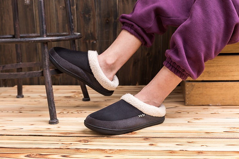 Schwarze Herren-Baumwollhausschuhe mit weißem Futter, ideal für Winter, auf Holzfußboden.