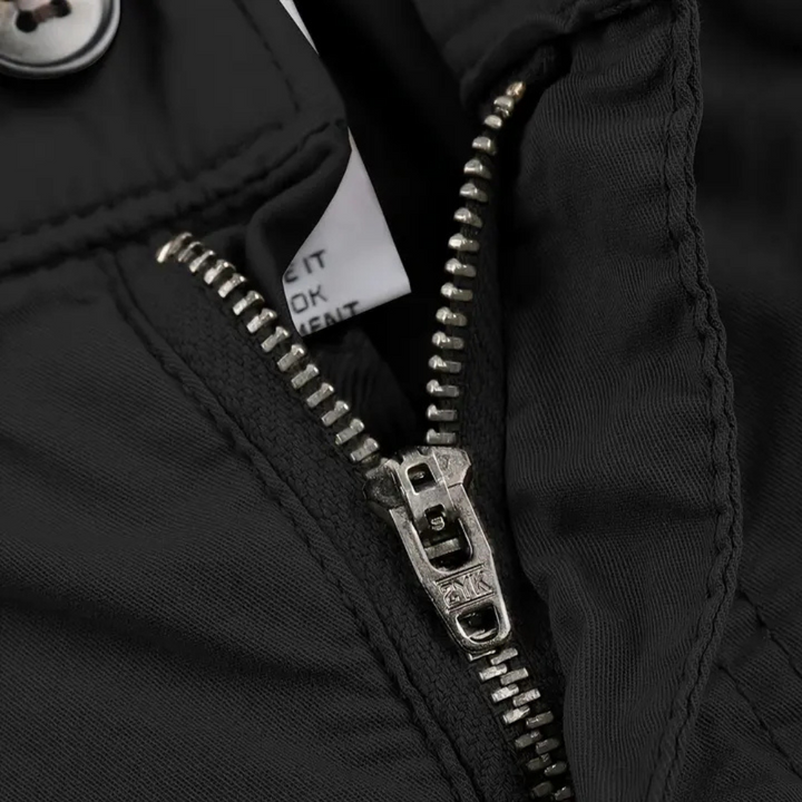 Schwarzer Reißverschluss an Jacke, Nahaufnahme, Metallzähne, robuste Verarbeitung.