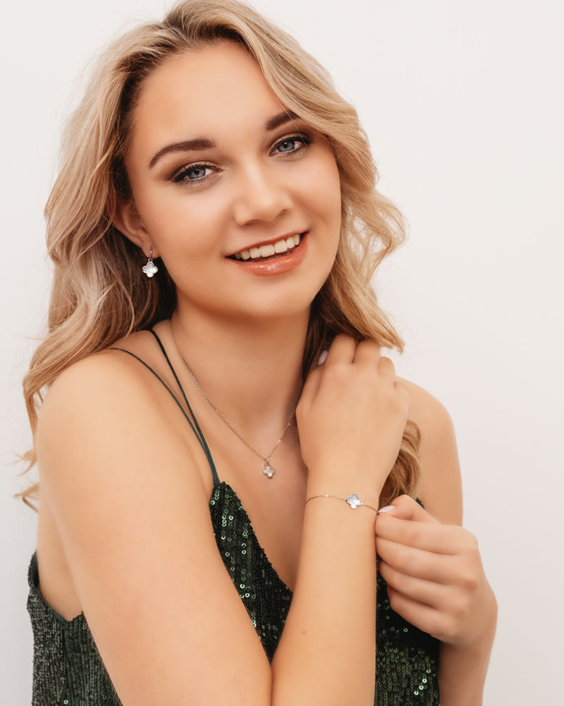 Frau mit silbernen Kleeblatt-Schmuck, Ohrringe, Halskette, Armband, grünes Kleid.