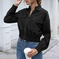 Frau in schwarzer Bomberjacke, Jeans, hält Kaffeebecher, urbaner Hintergrund.