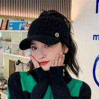 Frau mit schwarzer Strickmütze mit Schirm, modisch, warm, Winteraccessoire, stilvoll.