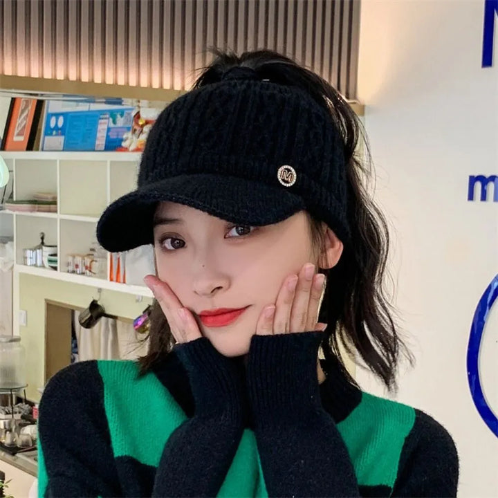 Frau mit schwarzer Strickmütze mit Schirm, modisch, warm, Winteraccessoire, stilvoll.