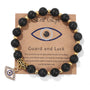 Schwarzes Natursteinarmband mit türkischem Auge, goldenen Perlen und Anhänger auf Karte.