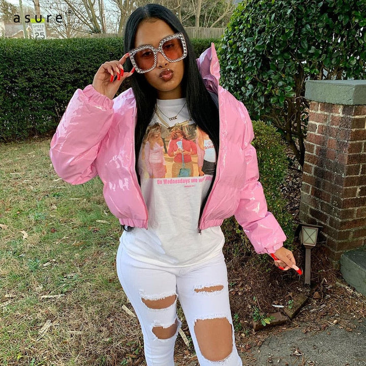 Frau in rosa Daunenjacke, zerrissene weiße Jeans, große Sonnenbrille, modischer Streetstyle.