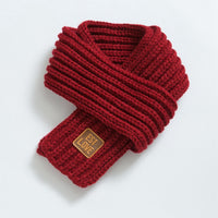 Roter Strickschal aus Wolle mit Lederetikett, modisches Winteraccessoire für Damen und Herren.