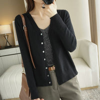 Frau in schwarzem Cardigan und grauem Top, braune Hose, modisch, lässig, Innenraum.